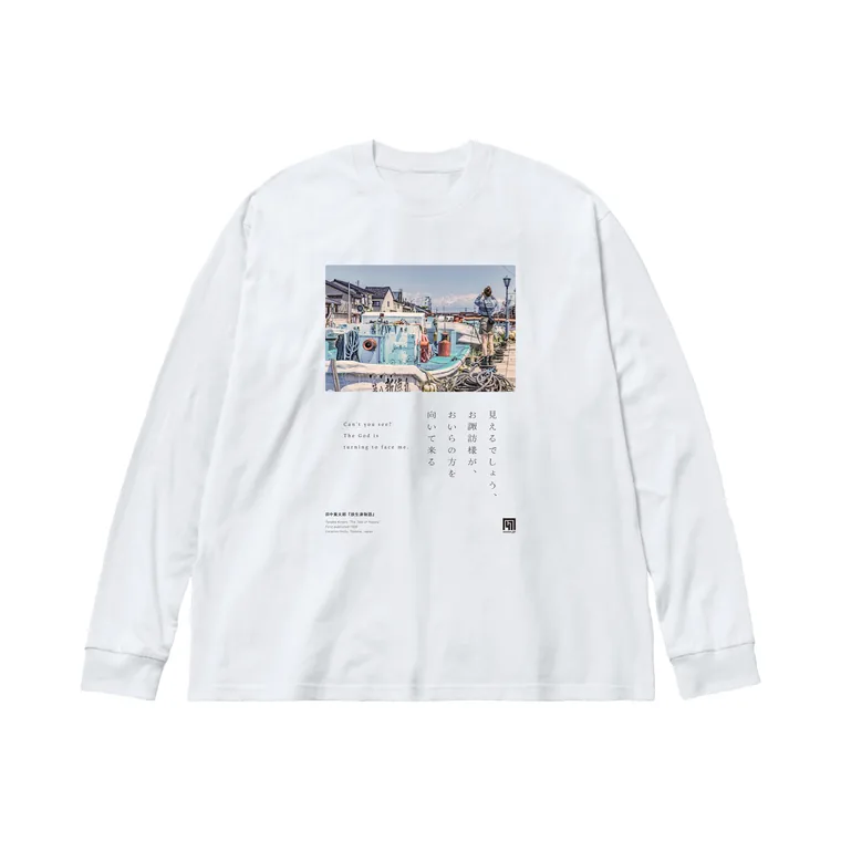 『放生津物語』のTシャツ。白い長袖に、放生津・内川の風景と源吉の言葉『見えるでしょう、お諏訪様が、おいらの方を向いて来る』を配した一枚。