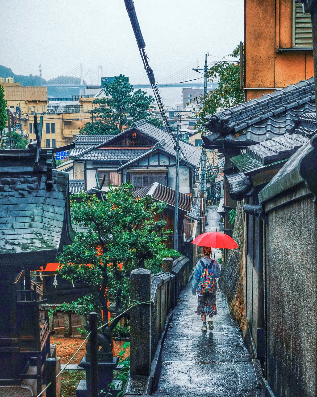 尾道の坂道と海——雨に濡れた石段、瓦屋根の町並みの向こうに尾道水道と橋