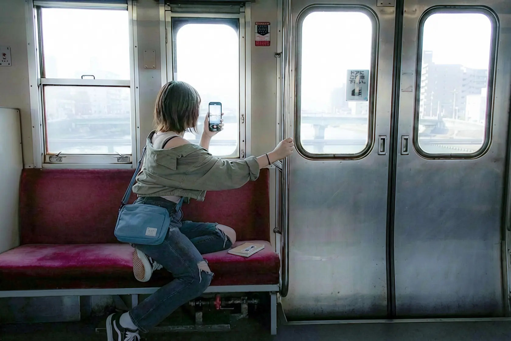 赤いシートの並ぶ古い車内。窓の外に曇りの景色が流れる。