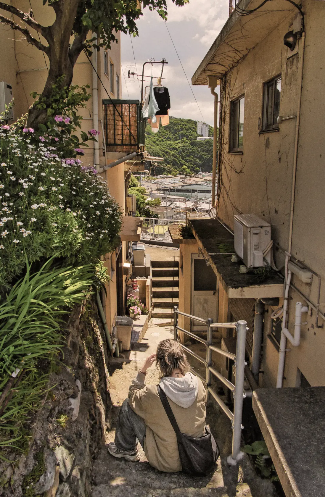 和歌山市・雑賀崎の漁港へ下る路地の階段。手前に腰かける巡礼者の姿。